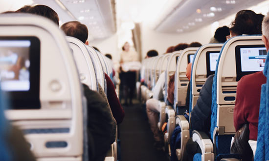 Flygplansinteriör där man ser stolsryggar och människor som sitter på plats 