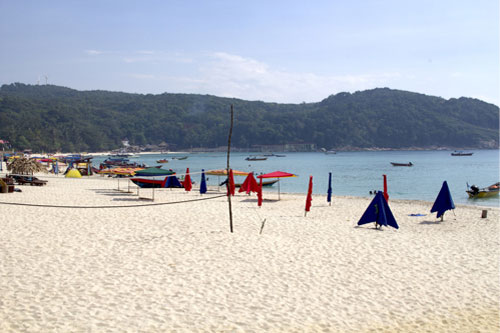 Fin strand med volleybollnät och parasoll på Perhentian Islands i Malaysia