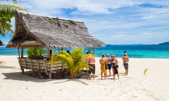 En bar i trä som står på en vacker sandstrand med havet bakom