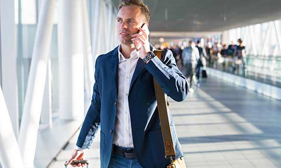 Manlig tjänsteresenär som pratar i mobiltelefon på flygplats