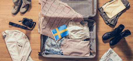 Resväska packad med kläder och en svensk flagga