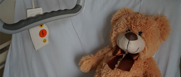 En brun leksaksnalle som ligger i en sjukhussäng