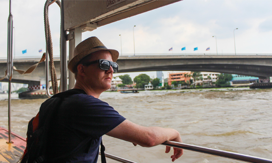 Patrik Enlund på backpackerresa. Han står vid en strand.