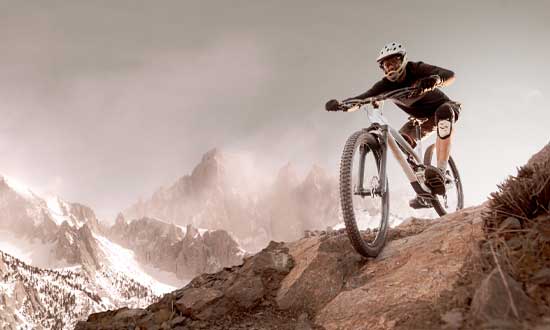 Man som utför downhillcykling. I bakgrunden syns berg.