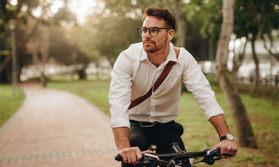Man med datorväska som cyklar i parkmiljö
