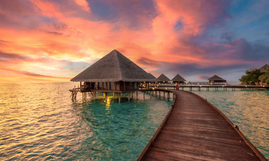 En bungalow ute på havet i Västindien. Solnedgången lyser vackert bakom.